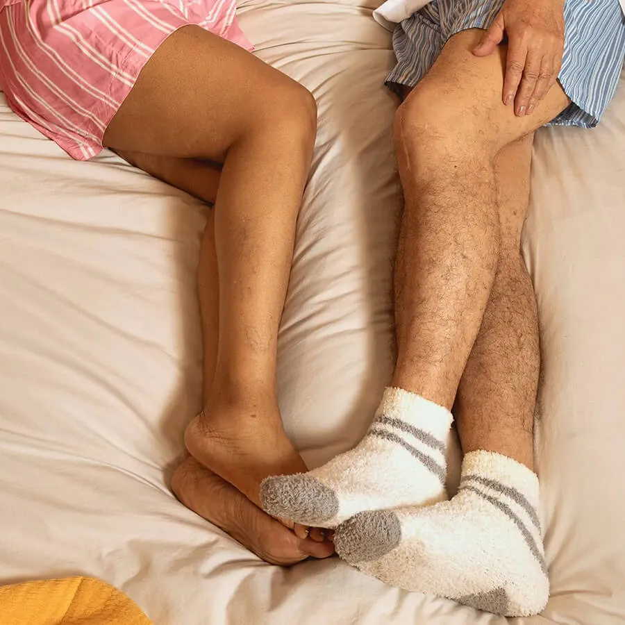 sleep quality and vein health, man and woman's legs laying in bed