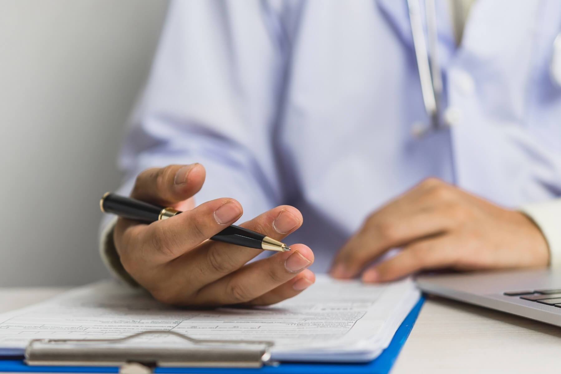 M&eacute;dico con bata blanca revisa documentos en una tablilla