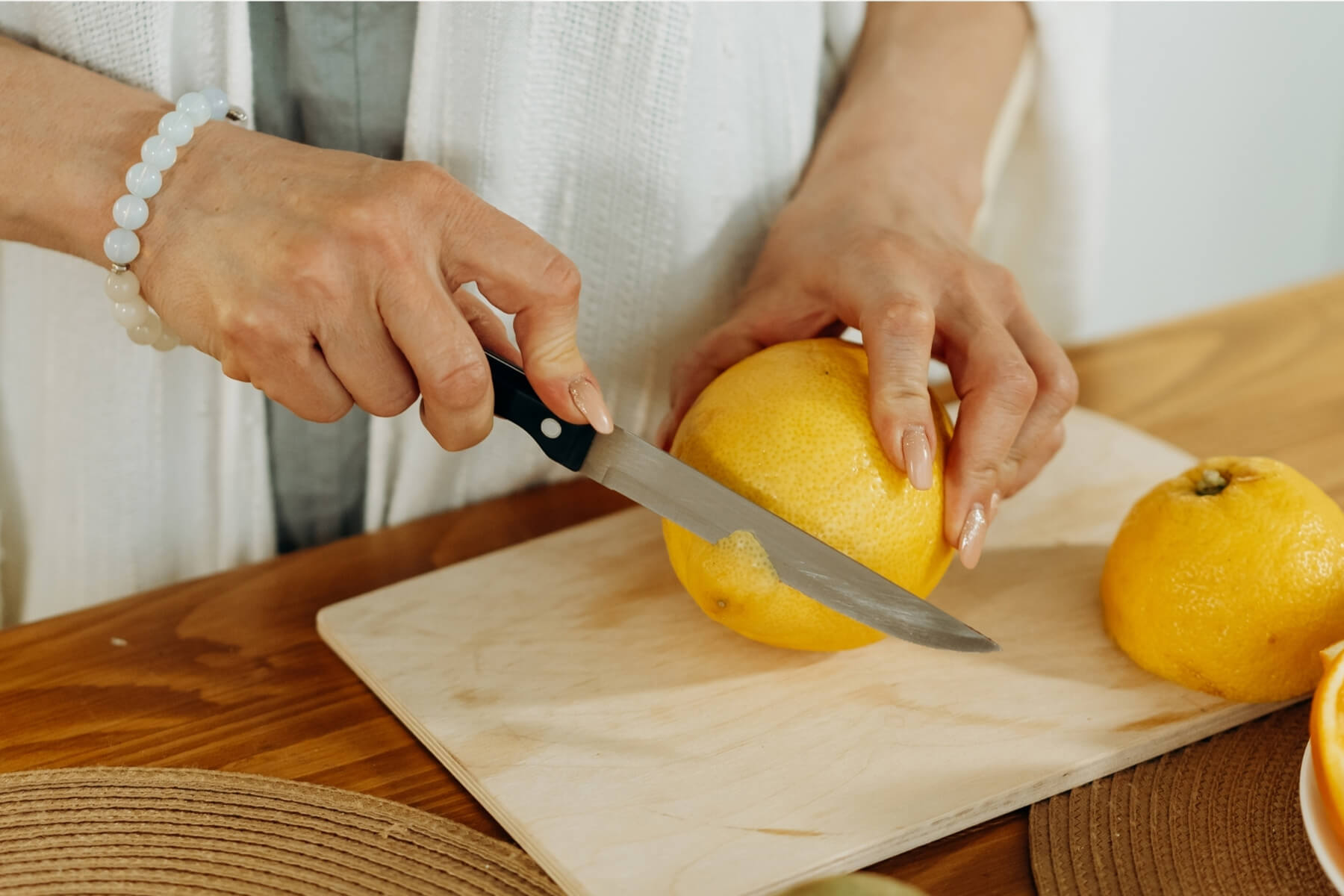Persona cortando naranjas frescas sobre una tabla de madera