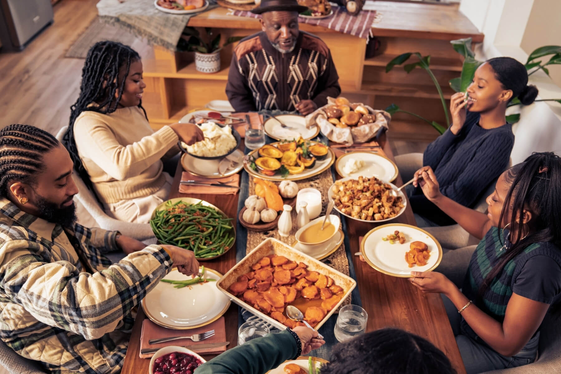 Familia compartiendo una cena de Acción de Gracias con guarniciones de verduras en la mesa